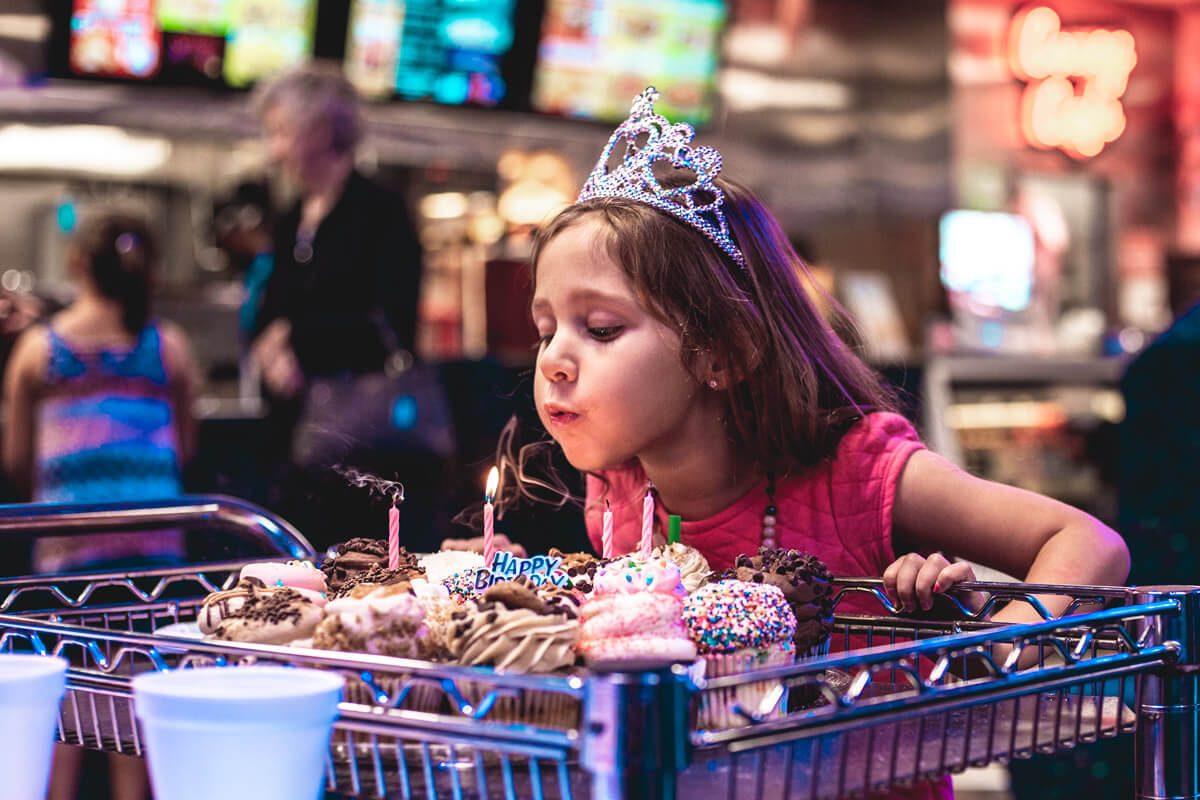 5 year old blows out candles on birthday cupcakes