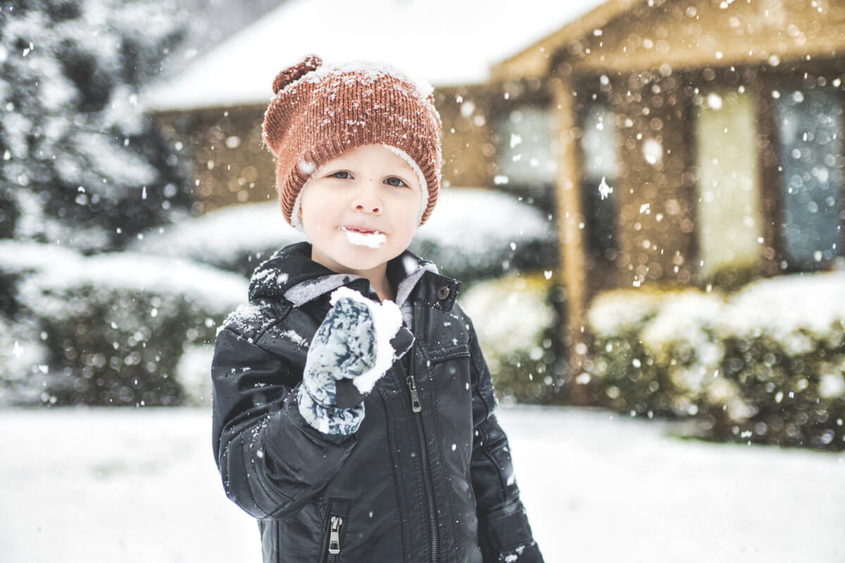 3 year old holds up a snowy glove and has a mouth covered in snow