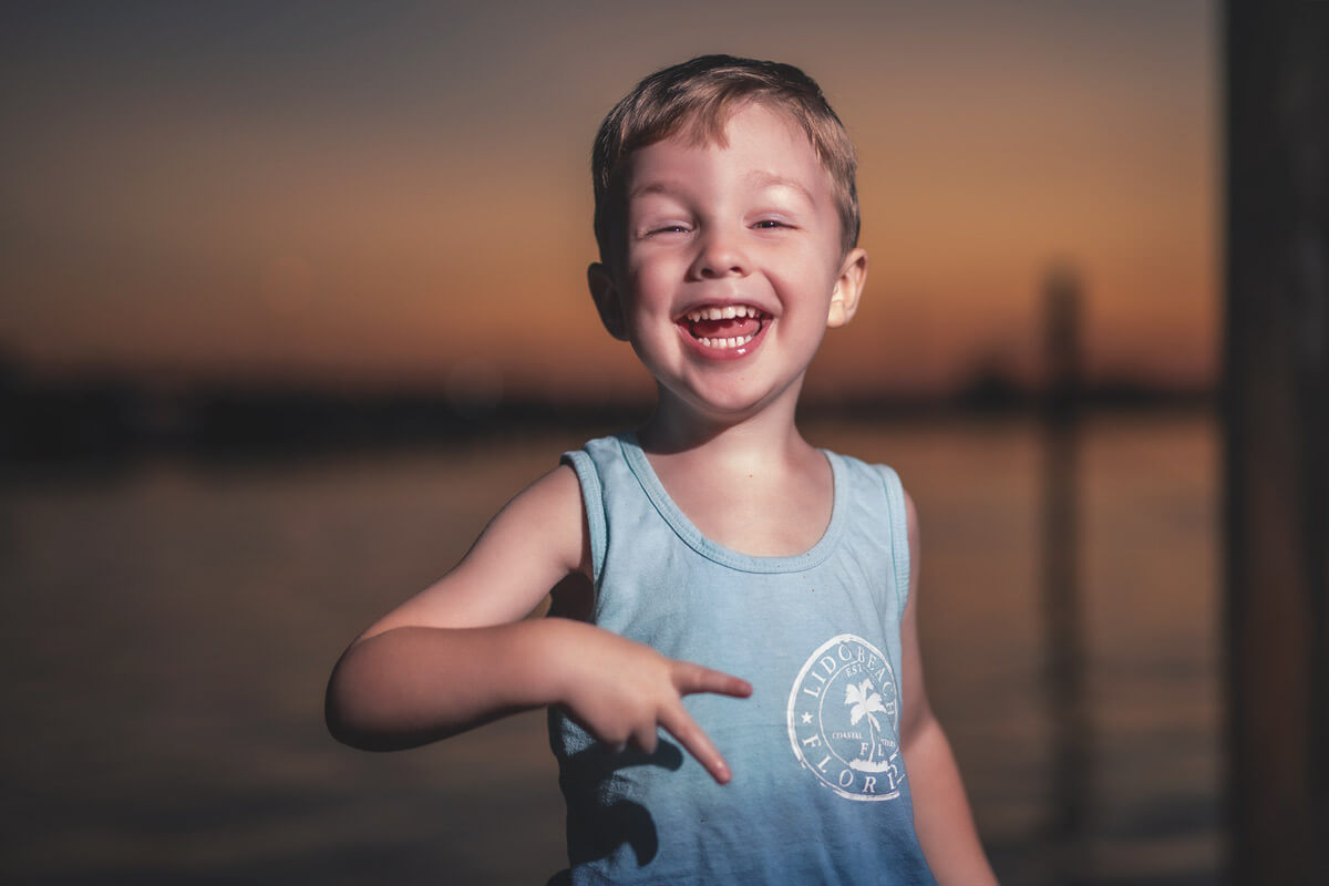 4 year old holds up a peace sign and is laughing