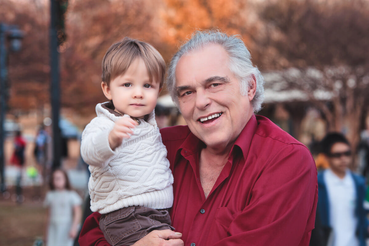 Grandfather is smiling while holding toddler